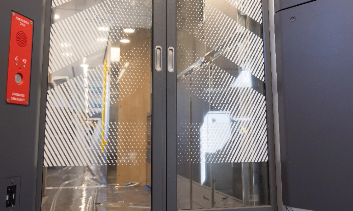 Photo d'une porte de verre avec deux panneaux coulissants automatiques à bord d'un train. 